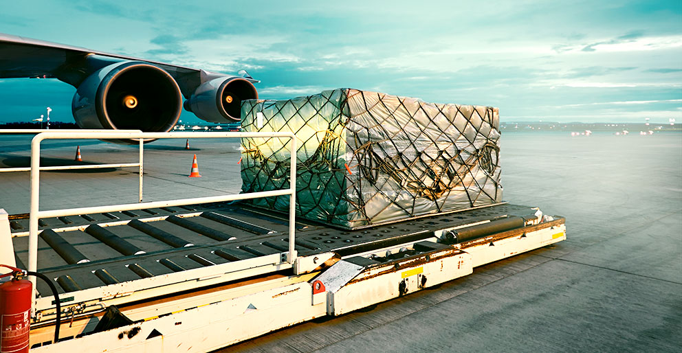 Freight on a conveyer belt outside at the airport being loaded onto or unloaded from a cargo plane